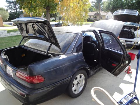 1995 Ford Taurus - Dark blue sedan, possibly a 1995 Ford Taurus, with doors and trunk open. Another vehicle is visible in the background.