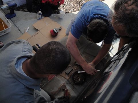 1995 Ford Taurus - Mechanics work on a car's fuel tank, which has been removed for service.