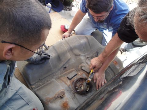1995 Ford Taurus - Mechanics are shown working on a car's fuel tank, likely in the process of removing or replacing the fuel pump assembly.