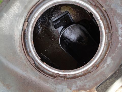 1995 Ford Taurus - Close-up view of a vehicle's fuel filler neck opening, showing a black hose and rusty metal components.
