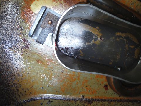 1995 Ford Taurus - The oil pan and drain plug show signs of wear and accumulated grime.