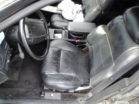 1995 Ford Taurus - Worn interior of a car with black leather seats and a steering wheel visible.