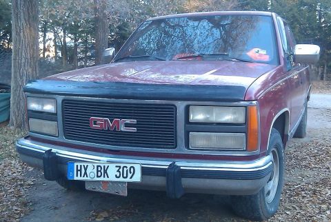 2000 Mercury Grand Marquis - A red GMC pickup truck is shown from the front, its distinctive grille and headlights.