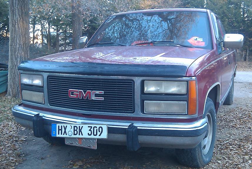 Red GMC pickup truck front view with license plate HX BK 309