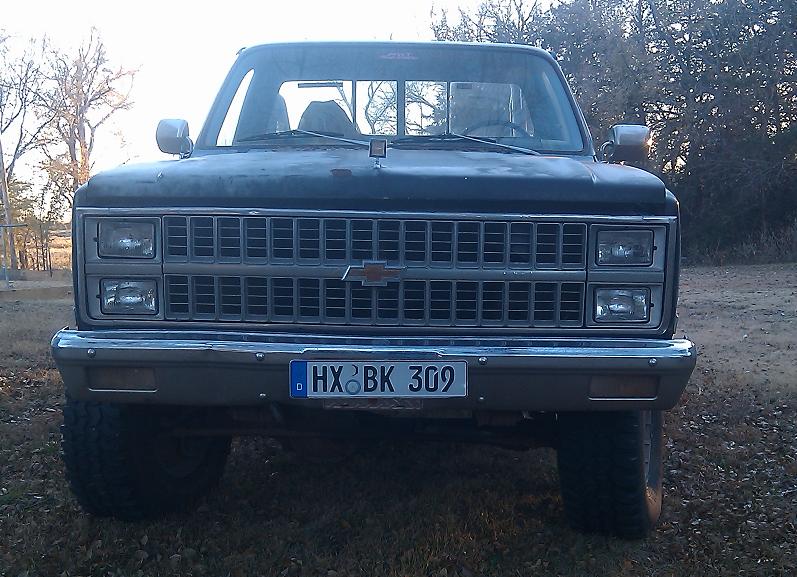 Front view of a dark-colored Chevrolet pickup truck with a chrome grille and license plate HX BK 309
