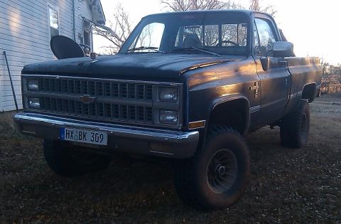 2000 Mercury Grand Marquis - A lifted Chevrolet pickup truck sits parked outdoors in front of a house.