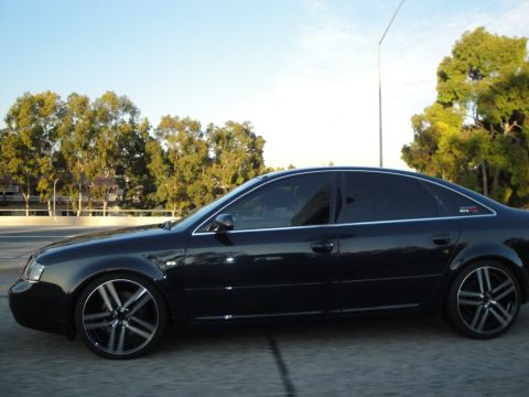 1995 Ford Taurus - Side view of a black sedan with tinted windows and custom wheels on a highway.
