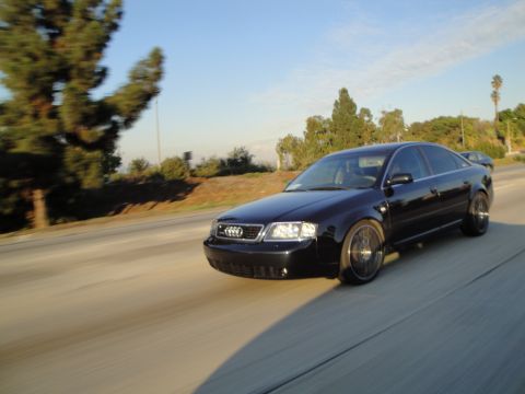 1995 Ford Taurus - A black Audi sedan is captured in motion on a highway under a clear blue sky.