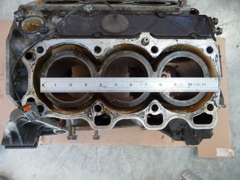 1993 Mazda MX-3 - A ruler is placed across the cylinders of an engine block, likely for measurement purposes.