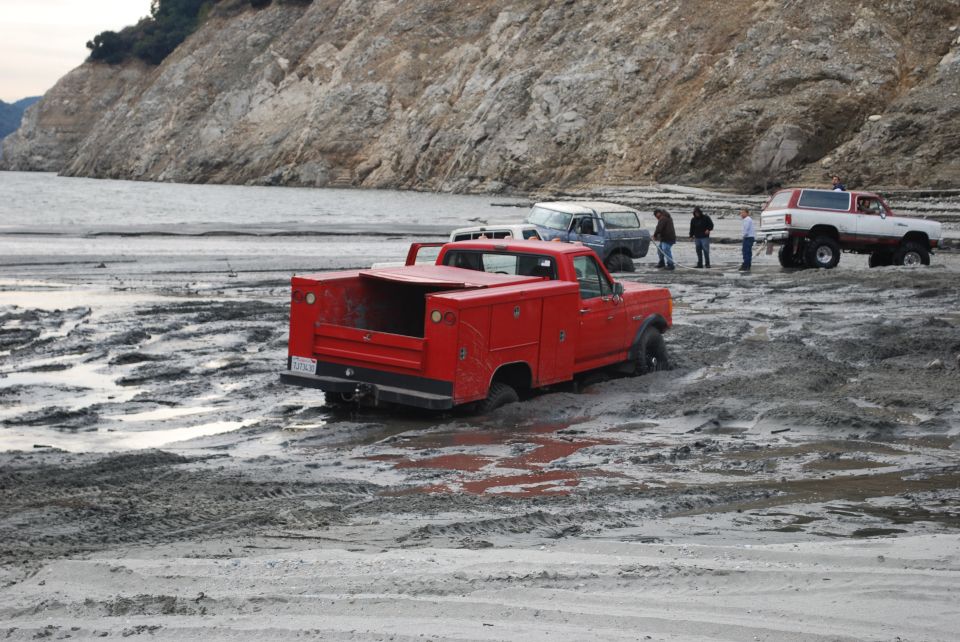 Red pickup truck with toolboxes stuck in mud, rear view