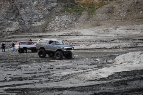 1996 Ford Bronco - Two off-road vehicles navigate a dry, rocky terrain.