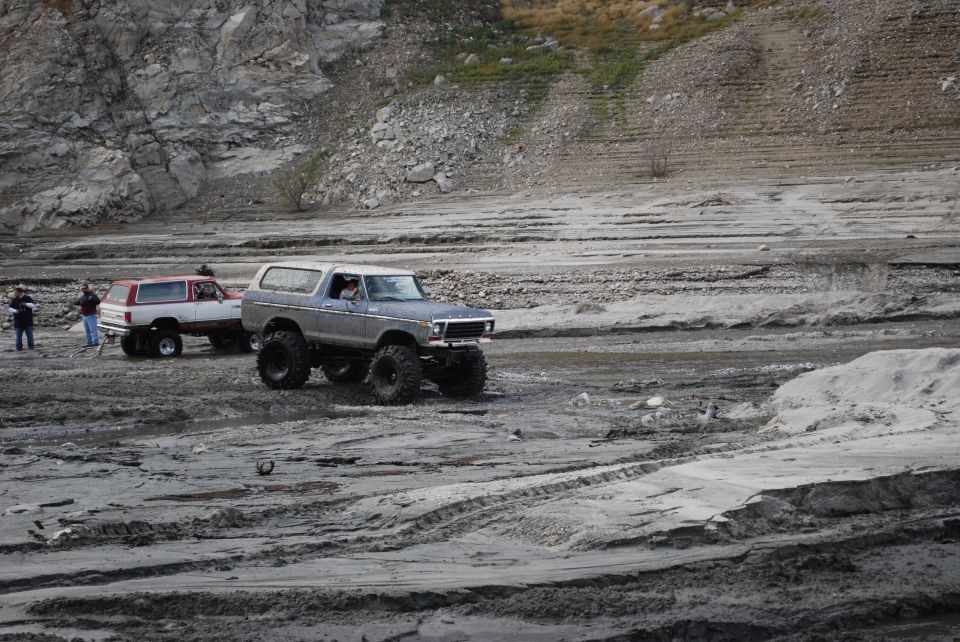 Gray Ford Bronco with large tires driving on a dirt track