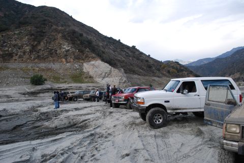 1996 Ford Bronco - A group of SUVs, including a white 1996 Ford Bronco, are gathered in a rocky, mountainous terrain.