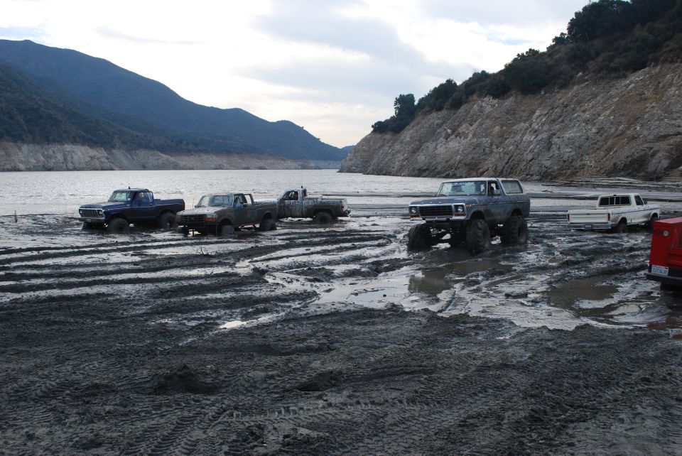 Gray Ford Bronco with large tires on muddy ground near water