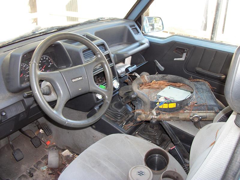 1989 Suzuki Sidekick interior with worn seats, dashboard, steering wheel, and exposed radiator