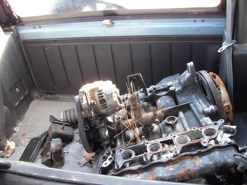 Disassembled four-cylinder engine block with exposed bores in vehicle cargo area