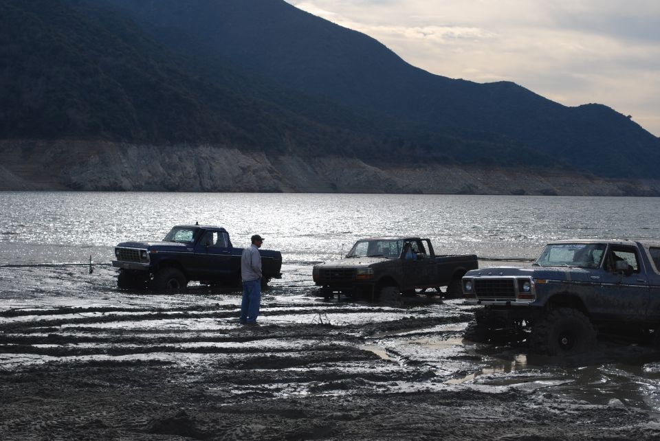 Three trucks stuck in mud, one is a 1979 Ford F-Series