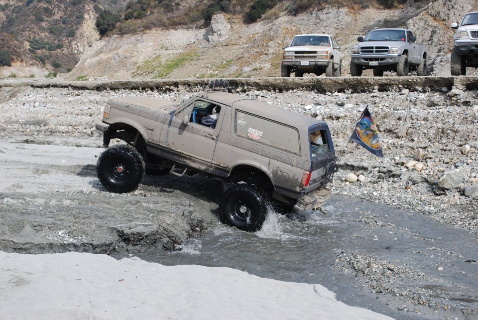 1996 Ford Bronco driving through water, lifted with large tires
