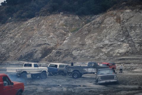 1996 Ford Bronco - A group of off-road vehicles are gathered in a desolate, rocky area, with a steep, eroded hillside dominating the background.