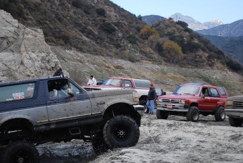 1996 Ford Bronco - Several off-road vehicles, including a Ford Bronco, navigate a challenging, mountainous landscape.