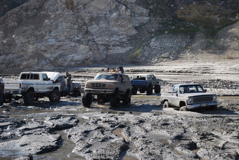 Tan Ford Bronco with lifted suspension stuck in mud, front view