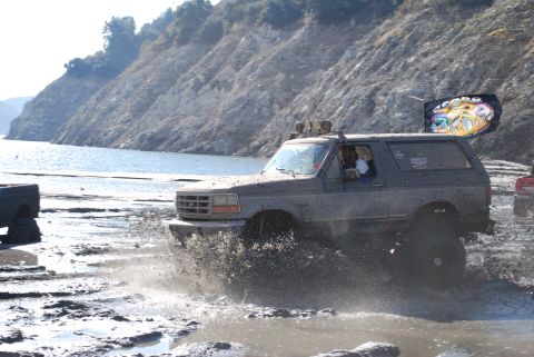 1996 Ford Bronco - A Ford Bronco navigates a muddy terrain with a flag attached to its roof.