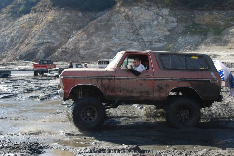1996 Ford Bronco - Muddy off-road adventure with a classic Ford Bronco and other trucks.