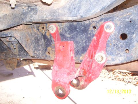 1978 Ford Bronco - Close-up of a red painted suspension part bolted to a vehicle's frame.