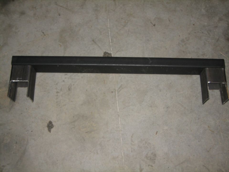 Black metal bracket with U-shaped ends, resting on a concrete floor