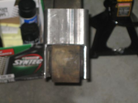 1984 Ford Bronco - A metal bracket and roller assembly is shown, with a bottle of Syntec oil and a jack stand in the background.