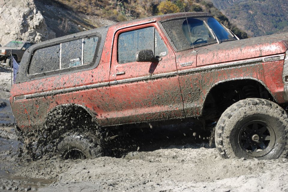Red SUV stuck in mud, another vehicle visible in background