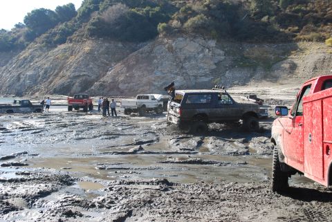 1996 Ford Bronco - Several off-road vehicles navigate a muddy terrain, including a 1996 Ford Bronco.