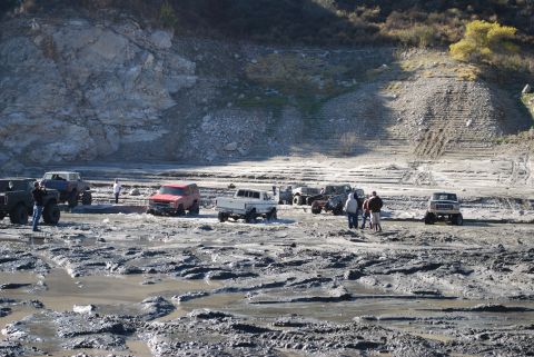 1996 Ford Bronco - Multiple off-road vehicles are seen in a muddy, rocky area, suggesting an off-road event or gathering.