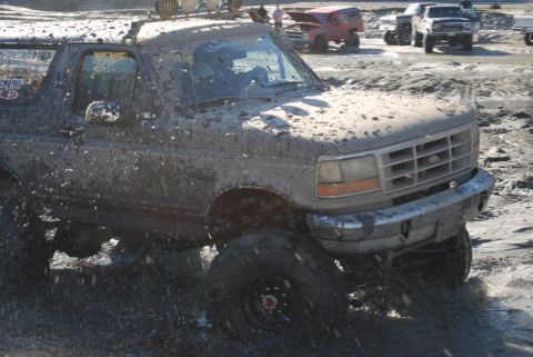 1996 Ford Bronco - Muddy 1996 Ford Bronco navigating rough terrain; other off-road vehicles visible.