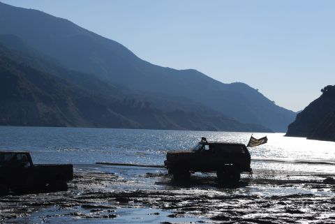 1996 Ford Bronco - A 1992 Ford Bronco navigates muddy terrain by a lake, with another vehicle visible to the left.