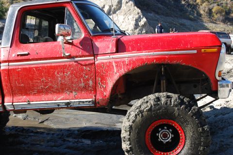 1996 Ford Bronco - This red 1979 Ford F-Series pickup truck features a lifted suspension and large off-road tires, suggesting it's built for terrain.