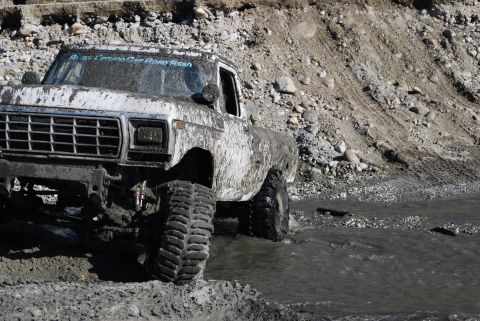 1996 Ford Bronco - Mud-splattered truck navigates a watery, rocky terrain, with 'El Centro Off Road Assn' visible on the windshield.