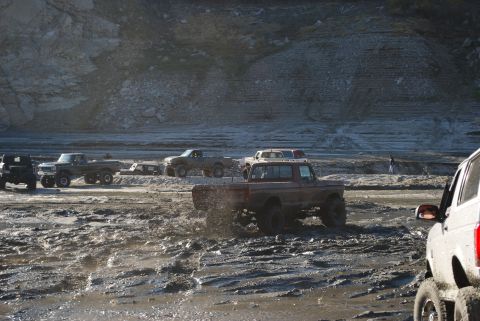 1996 Ford Bronco - Modified trucks navigate a challenging muddy terrain during an off-road event.