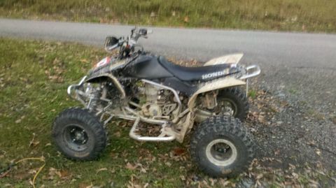 2003 Chevrolet Silverado 1500 - A black Honda ATV is parked on the side of a road, covered in dirt.