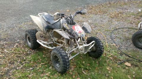 2003 Chevrolet Silverado 1500 - A muddy ATV sits on grass and gravel, with another ATV visible in the background.