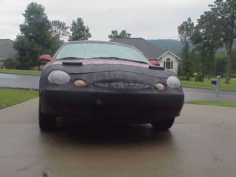 1998 Ford Taurus - A car is parked outside on a cloudy day, its front end covered by a car bra.