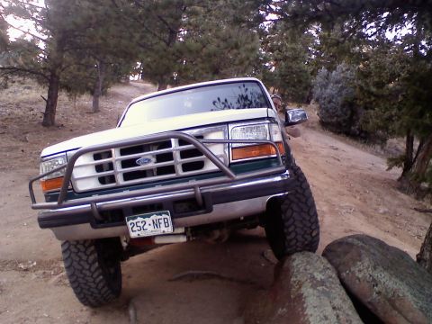 1996 Ford Bronco - A 1996 Ford Bronco navigates a rocky off-road path with its front end angled towards the camera.