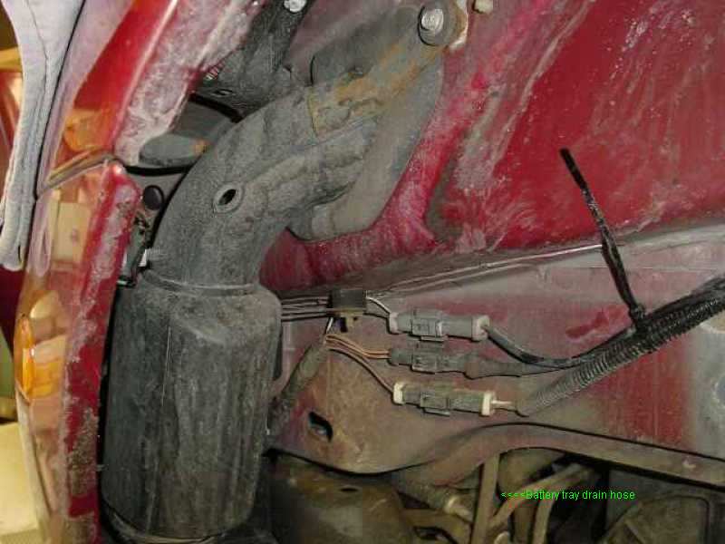 Red vehicle fender well with black drain hose and electrical connectors