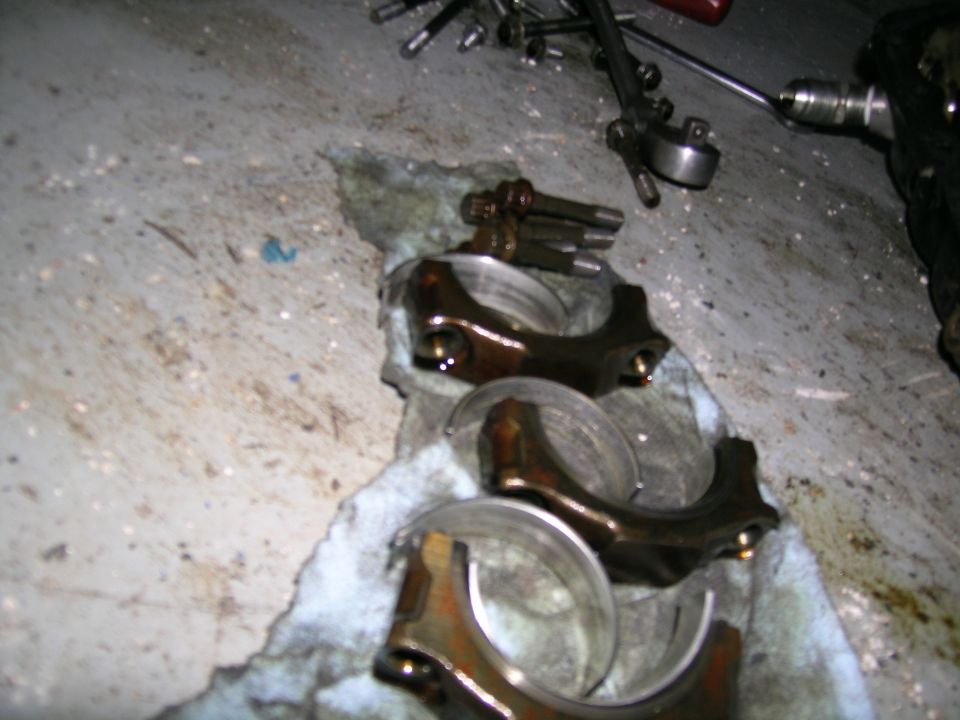 engine connecting rods and bearings laid out on a rag with tools nearby