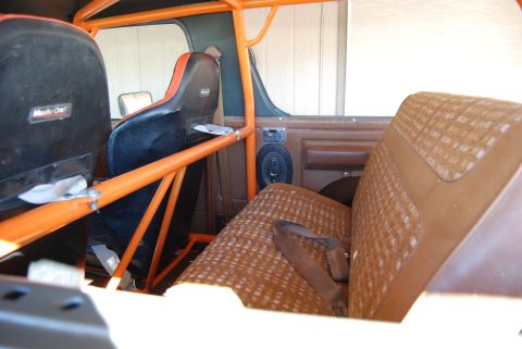 1982 Ford Bronco - The interior of a 1982 Ford Bronco shows racing seats and a roll cage, along with the original bench seat.