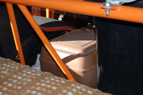 1982 Ford Bronco - A brown cooler is visible inside a vehicle, behind orange roll cage tubing and next to black seats.