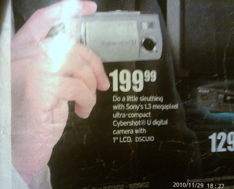 2000 Mercury Grand Marquis - A hand holds a Sony Cybershot digital camera, advertised with its price and features.