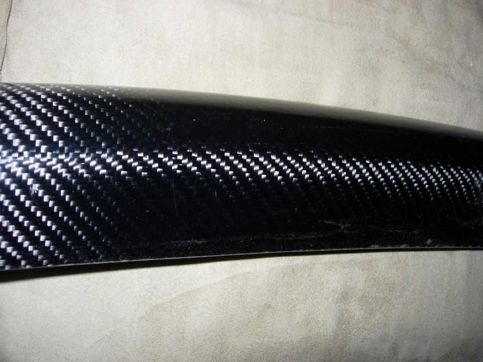 Close-up of glossy carbon-fiber twill weave on a curved body trim piece