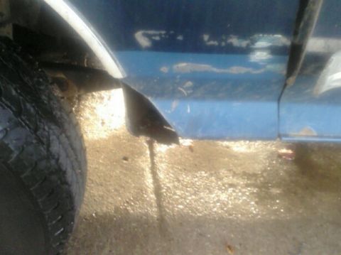 1989 Ford Bronco - Close-up of a vehicle's lower body panel and tire, showing some rust and dirt.