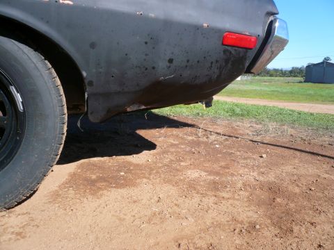 1975 Ford Ranchero - The rear of a dark-colored vehicle, showing its fender, bumper, and taillight, with a "SUPERMOTORS" watermark.